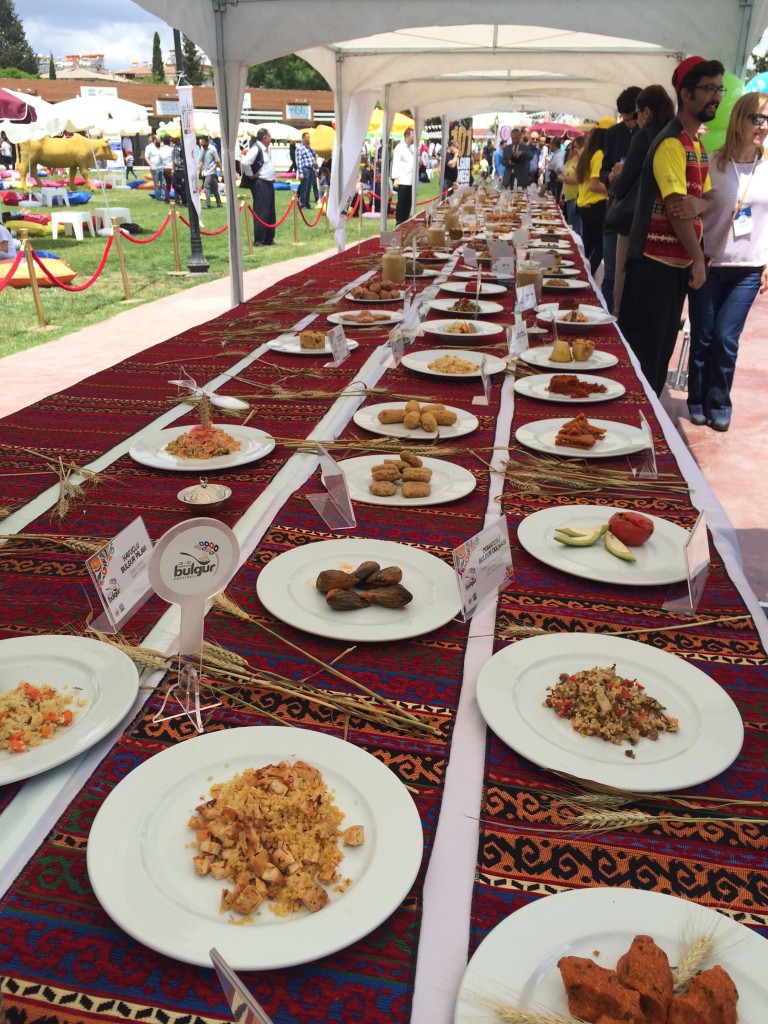 Table set with 101 different dishes using bulgur, including sushi, cheesecake, stuffed eggplants, artichoke and pineapple